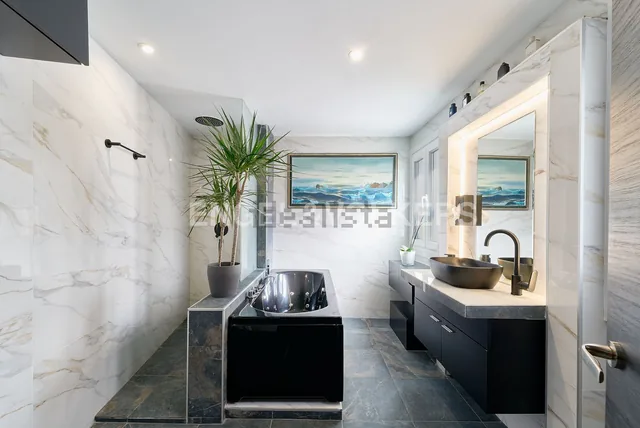 Wide bathroom view with jacuzzi bath, wall artwork and vanity