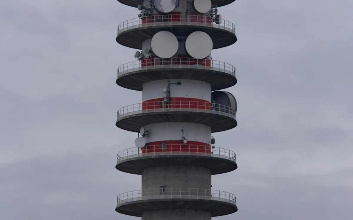 Telecommunications tower with microwave dishes and radio antennas against an overcast sky